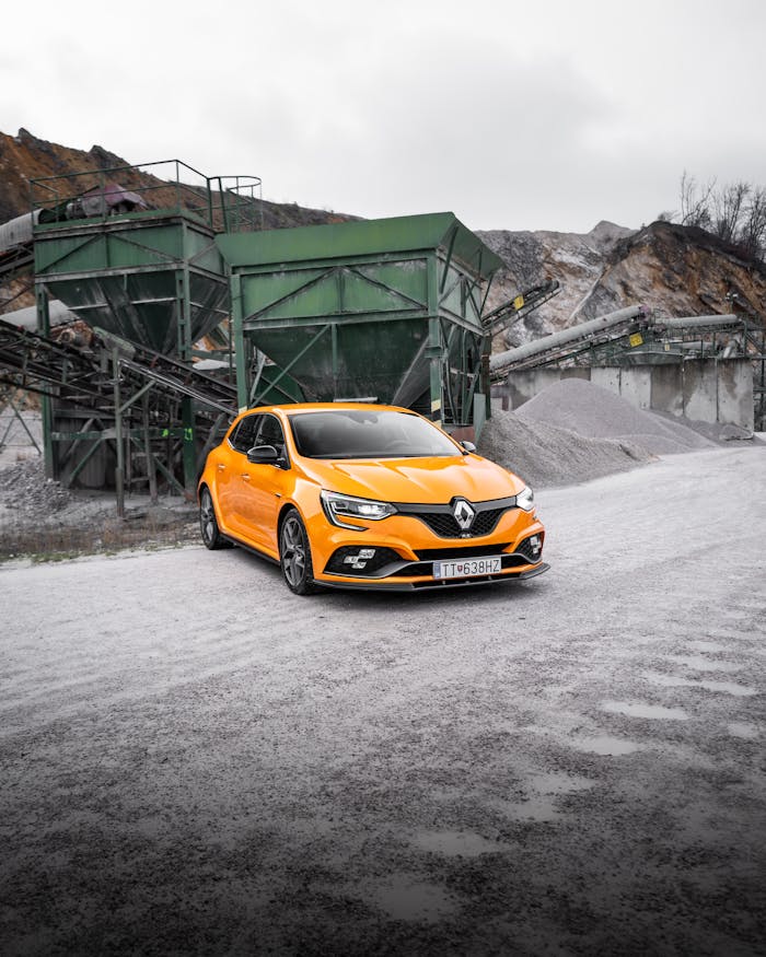 A vibrant yellow Renault Megane parked in an industrial landscape.